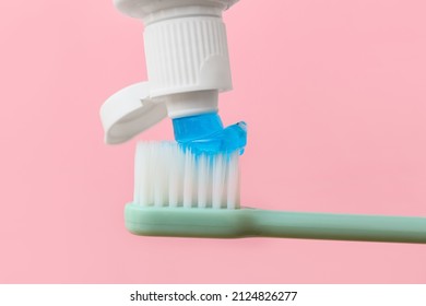 Squeezing Tooth Paste Onto Brush On Pink Background, Closeup