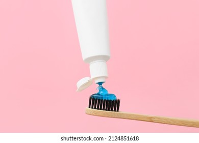 Squeezing Tooth Paste Onto Brush On Pink Background