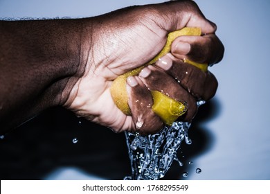 Squeezing A Wet Sponge In A Bright Background.