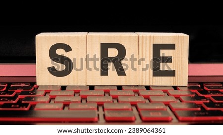 SRE. Site Reliability Engineering written on wooden cubes on the laptop keyboard