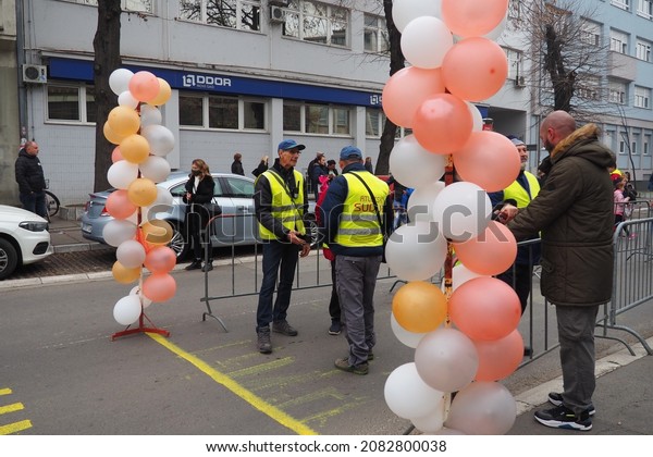 Sremska Mitrovica, Serbia, November 22, 2021 Sports\
competition and cross-country schoolchildren. Finish line, fences\
and inflated colorful balloons. Coaches in vests. City street and\
cars
