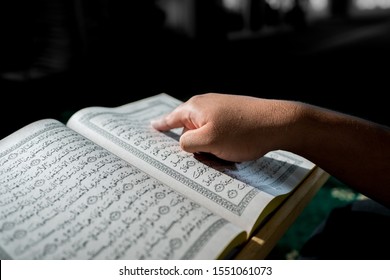 Sri Kembangan,Selangor - OCT 2019 :  al-Quran is a holy book of Islamic guidance isolated. religion concept. An open page of Quran on wooden stand above prayer mat open page of Quran on wooden stand