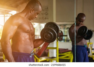 Sri Lankan Bodybuilder Man Lifting Dumbbell At Mirror. Sportsman Doing Exercises With Dumbbells At Old Gym. Athletic Asian Man Pumping Up Muscles Workout. Sports And Bodybuilding Concept. Copy Space