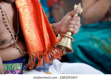 Sri Srinivasa Perumal hindu temple.  Hindu priest ( Brahmin ) performing puja ceremony  and rituals. Close up of hand holding ceremonial bell. Singapore. 