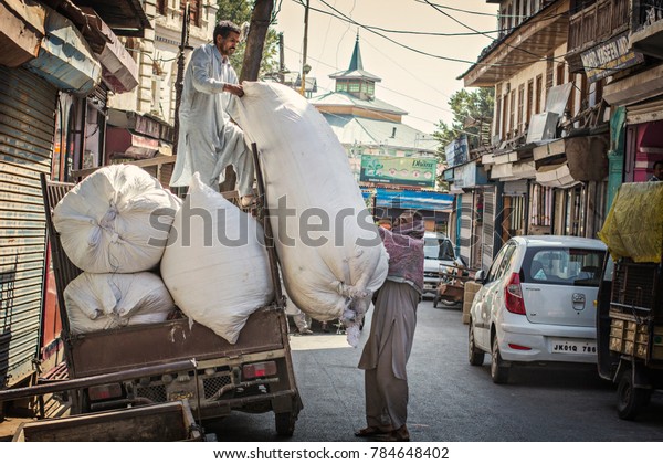 Srinagar, India - October 2017: Srinagar\
old town market. Indian men loading big bags with cotton onto the\
truck in Srinagar market, Jammu and Kashmir,\
India