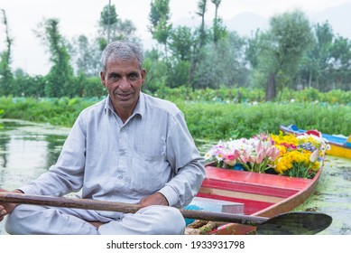 Srinagar, Jammu and Kashmir -22 JULY 2018 : elderly man rowing a dingy or a local boat called shikara in the dal lake selling some flower in the floating market