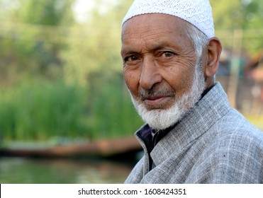 Srinagar, Jammu and Kashmir - April 25, 2018 : An elderly Kashmiri muslim man with grey beard and skull cap smilled at us sitting on his boat in the famous dal lake of srinagar.