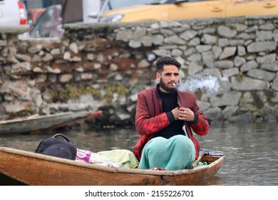Srinagar, Jammu and Kashmir, India - March 1 2022: A portrait of a Kashmiri Shikara boat sailor Indian man smoking on Dal Lake. The hands might be blurred due to motion.