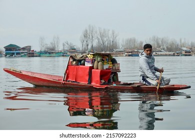 Srinagar, Jammu and Kashmir, India - March 1 2022: A portrait of a Kashmiri Shikara boat sailor and Fruits vendor  Indian man on Dal Lake during sunset. The hands might be blurred due to motion.