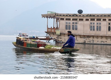 Srinagar, Jammu and Kashmir, India - March 1 2022: A portrait of a Kashmiri Shikara boat sailor and Vegetables vendor  Indian man on Dal Lake during sunset. The hands might be blurred due to motion.