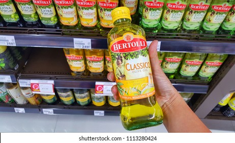 Sriracha, Chonburi THAILAND June 9, 2018: Man's Hands Are Holding Bertolli Olive Oil In Bottle On A Shelf In A Supermarket.