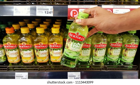 Sriracha, Chonburi THAILAND June 9, 2018: Man's Hands Are Holding Bertolli Olive Oil In Bottle On A Shelf In A Supermarket.