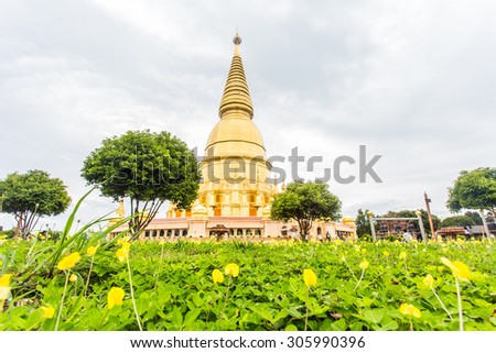 Sriwiengchai pagoda at Wat Phra Bat Huai Tom with soft focus green and yellow plant is the foreground. in Lamphun Thailand (Cloudy days with less sunlight)