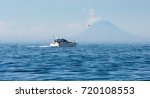 With St Augstine volcano in distance a sport fisherman sails their boat through small waves in Cook Inlet Alaska.