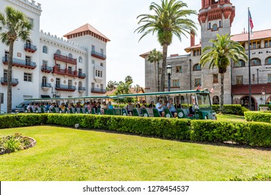 St. Augustine, USA - May 10, 2018: Flagler College With Florida Architecture, Famous Statue In Historic City, Grass Lawn And Trolley Tour Guide Tram