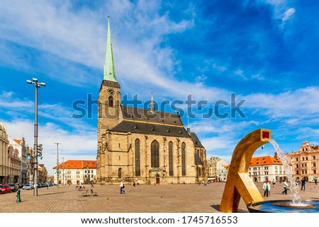 St. Bartholomew's Cathedral in the main square of Plzen with a fountain on the foreground against blue sky and clouds sunny day. Czech Republic, Pilsen. Famous landmark in Czech Republic, Bohemia.