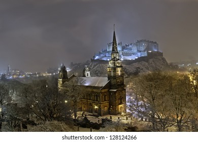 St. Cuthbert's Church, Edinburgh Castle, And Surrounding City Skyline Illuminated At Night During Winter Snow Fall.