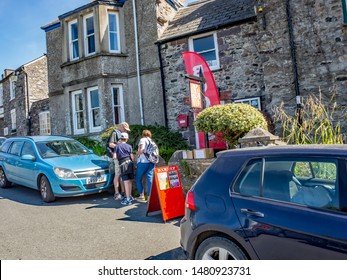 St Davids, Wales, UK – July 09 2019. Tourists In St Davids Perusing The Books Available For Sale In The Second Hand Book Store Along The Pebbles