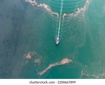 St Dogmael's, Pembrokeshire, Wales - August 2022: Overhead View Of Pattern Made By The Wake Of A Small Motor Boat With People Aboard As It Sails Through Sea Foam And Debris On The Estuary At High Tide