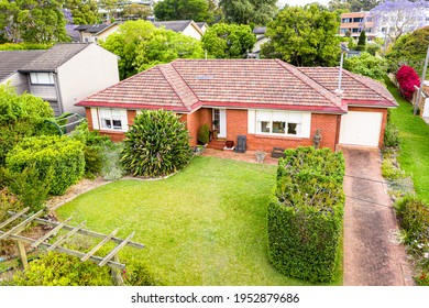 St Ives, Sydney, Australia - Nov 12 2020: Aerial Pole Shot Of Single Story Red Brick 70's Suburban Home With Front Garden And Lawn