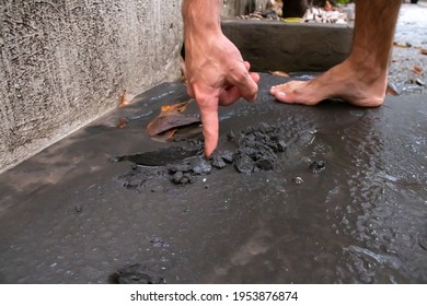 St. James, Barbados - April 11 2021: White Man Drags Finger Through Wet Volcanic Ash From St. Vincent's Soufriere Volcano Eruption. Severe Ash Fall On The Island, Consistency Of Cement.