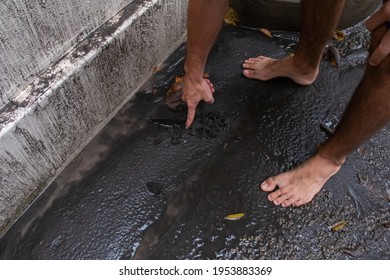 St. James, Barbados - April 11 2021: White Man Drags Finger Through Wet Volcanic Ash From St. Vincent's Soufriere Volcano Eruption. Severe Ash Fall On The Island, Consistency Of Cement.
