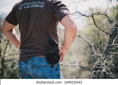 St. Jo, Texas / USA - March 28, 2020: Close Up Rear View Of A Man Wearing An Open Carry Handgun In A Holster At His Belt While Outside