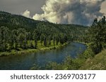 THE ST JOE RIVER IN IDAHO WITH LUGH GREEN TREES AND A CLOUDY SKY