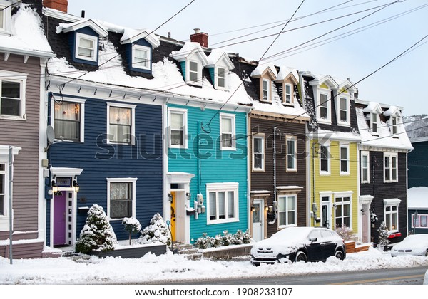 St. John\'s, Newfoundland, Canada - February 2021:\
Streetview of multiple colourful row houses in downtown St. John\'s\
after a large snowfall. There\'s white snow on the roofs, dormers\
and sidewalks. 