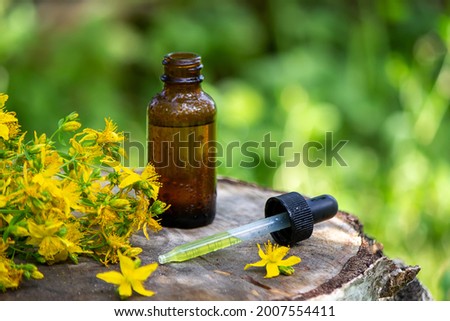 St. John's wort flower oil in a glass bottle. on a wooden background. Selective focus