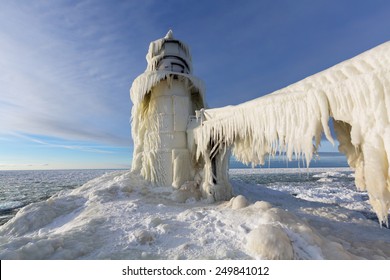 St. Joseph Pier Lighthouse frozen in winter. The catwalk is draped with ice curtains and the light is encased from furious Lake Michigan storms and winds