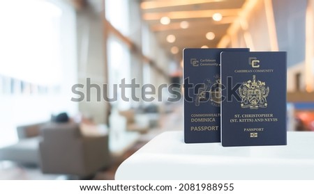St Kitts and Nevis and Dominica passports on a white table, in the background the boarding hall 