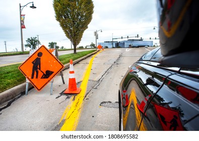 St. Louis, Missouri, USA, Sept. 3, 2020 - Orange Construction Caution Sigh Men At Work On Street, Orange Safety Cone, Car Stopped In Street, Repair Work, Warning, Man Shoveling Dirt, Residential