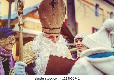 St Nicholas Meeting A Child On The Christmas Market While The Family Waits In The Background