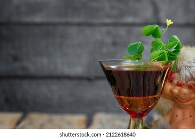 St. Patrick's Day. Clover, imp, glass of wine on a wooden background