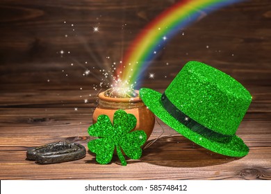 St Patricks day decoration with magic light rainbow pot full gold coins, horseshoe, green hat and shamrock on vintage wooden background, close up