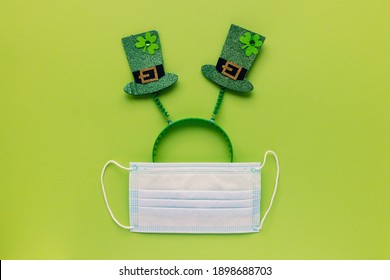 St Patricks Day During Coronavirus Concept. Headband With Hats And Mask On Green Background. COVID-19 Quarantine, Safe Celebration And Stay Home Concept. Top View, Flat Lay, Copy Space