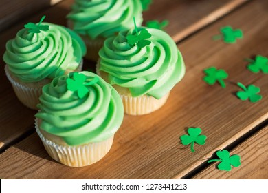 st patrick's day, food and holidays concept - close up of green cupcakes and shamrock on wooden table - Powered by Shutterstock
