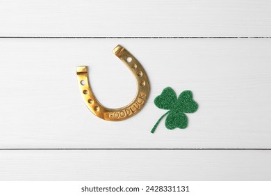 St. Patrick's day. Golden horseshoe and green decorative clover leaf on white wooden table, flat lay - Powered by Shutterstock