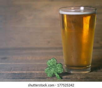 St. Patricks Day Green Shamrock And Frosty Cold Glass Of Beer On Wood Background With Room Or Space For Text, Copy, Words.  Vintage Camera Instagram Treatment.