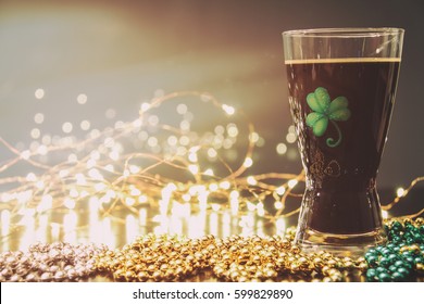 St Patricks Day Irish Stout Beer. Traditional Irish stout, a dark beer. On a pub bar rail table with lights and St Patrick's Day party beads. - Powered by Shutterstock