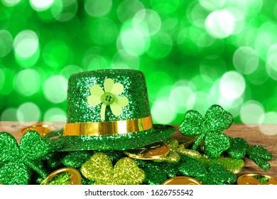 St Patricks Day leprechaun hat on a pile of gold coins and shamrocks in front of a twinkling green background