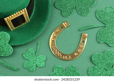 St. Patrick's day. Leprechaun hat, golden horseshoe and decorative clover leaves on green background, above view - Powered by Shutterstock