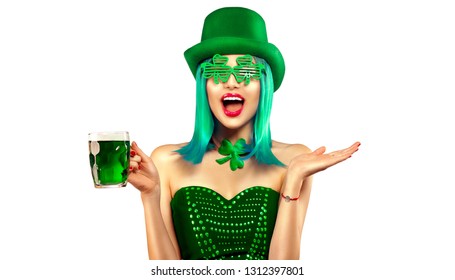 St. Patrick's Day leprechaun model girl in green hat holding mug of Green Beer pint over white background and pointing hand, Smiling. Patrick Day pub party, celebrating. Glass of Green beer. Ads