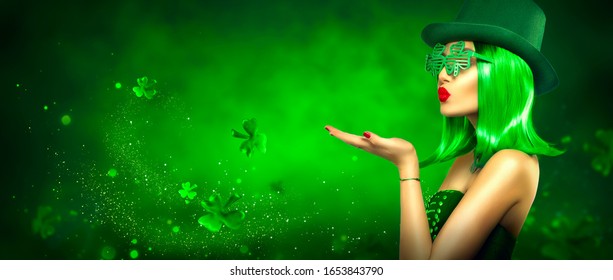 St. Patrick's Day leprechaun model girl pointing hand, holding product on green magic background, blowing flying shamrock leaves. Patrick Day pub party, celebrating. Border art design, Widescreen