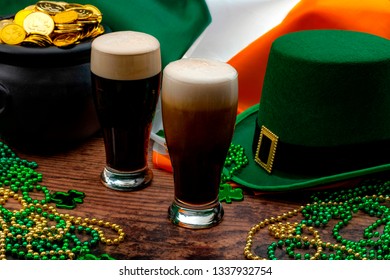 St Patricks day party and Irish celebration of patron saint concept theme with frothy glasses of dry stout, green hat with a buckle, a pot of gold, the flag of Ireland and beads with shamrock in a pub - Powered by Shutterstock