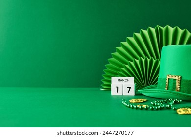 St. Patrick's Day revelry: a touch of emerald charm. Side view of green hat, calendar set to March 17th, green paper fan decoration, gold coins on green background with space for festive announcements - Powered by Shutterstock