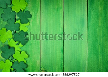 St Patricks Day side border of paper shamrocks over a green wood background