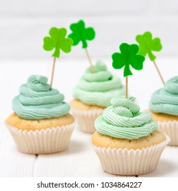 St. Patrick's Day Theme Colorful Square Banner. Cupcakes Decorated With Green Buttercream And Craft Felt Decorations In Form Of Shamrock Leaves On White Background With Copy Space For Greeting Card.