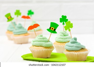 St. Patrick's Day Theme Colorful Horizontal Banner. Cupcakes Decorated With Green Buttercream And Craft Felt Decorations In Form Of Leprechaun Hat, Mustache And Shamrock Leaves On White Background.